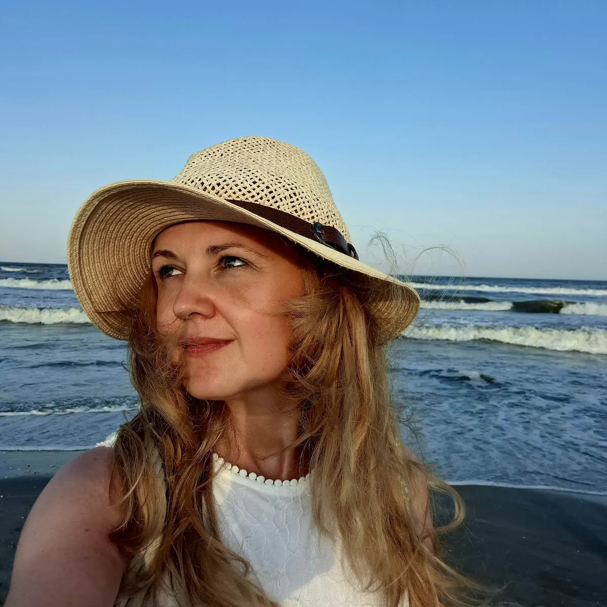 Alina Chercea wearing a straw hat by the sea